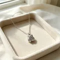 Detailopname van een zilveren uil hanger ketting op een beige sieraden dienblad - Staalkleur