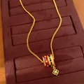 Close-up of a 24K gold plated necklace featuring enamel rings and a zircon floral pendant - Necklace / Gold-Red