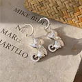 Nahaufnahme matter silberner Katzenohrringe mit funkelnden Strassaugen und Schleife - 3D Katzenstil / Silber