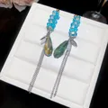 Gros plan détaillé de boucles d'oreilles à pampilles en cristal avec perles bleues et chaînes. - Boucles d'Oreilles Pendantes à Glands (Tige en Argent) / Bleu