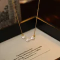 Macro view of 18k gold plated necklace featuring three elegant white pearls - Three Bead Pendant Style / Gold-White