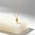 Nahaufnahme eines minimalistischen goldenen Blumenknospen-Anhängers aus Edelstahl. - Gold
