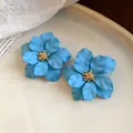 Makroansicht blauer matter Blumenohrringe mit goldenem Staubblatt auf weißem Tellerhintergrund - Blumenform / Blau mit Gold