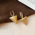 Detailopname van de geborstelde metalen textuur van deze gouden driehoek oorbellen. - Mat Goud