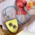 Macro detail of the yellow leather pendant with embroidered sun symbols and blue rope cord. - Sunflower Glasses Holder Style / Blue and Yellow Necklace