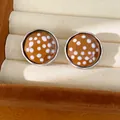 Macro view of ochre polka dot round stud earrings with a faceted glass finish and silver rim - Round Polka Dot Stud Earrings (HE35650) / Brown