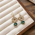 Close-up detail of vintage floral earrings with emerald green beads in a jewelry box - Ear Hook Earrings Only / Gold-Green