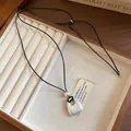 Detail view of a matte silver round pendant necklace on a cord in a wooden box - Matte Silver