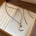 Close-up of a silver-toned metal pendant on a black adjustable cord necklace - Bright Silver