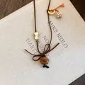 Macro view of a cute wooden dog pendant on a brown cord necklace laid over a beige book. - Dog
