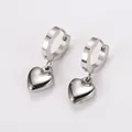 Close-up detail of silver stainless steel hoop earrings with polished smooth heart charms - Steel
