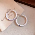Detaillierte Ansicht weißer Creolen mit blauen Punkten auf einem Leinen-Geschenkbeutel - Silbernadel-Weiß