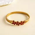 Gros plan détaillé d'un bracelet en acier doré avec trois fleurs en émail rouge - Bracelet jonc / Or-Rouge