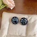 Detailaufnahme der runden Ohrstecker mit schwarz-weißen Punkten auf einem weichen Kissen - Schwarzes Punktmuster-Stil / Silber