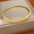 Detailansicht eines 18K vergoldeten Armreifs mit geripptem Design und funkelnden Zirkonen. - Gold