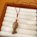 Primo piano di una collana con ciondolo a forma di pesce in legno su un vassoio. - Marrone chiaro