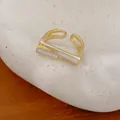 Detailansicht eines geometrischen vergoldeten Rings mit weißen Emaille-Einlagen - Gold