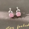Close-up of pink rose-shaped zircon earrings with leaf details on gray background. - Stud Earrings / Silver-Pink