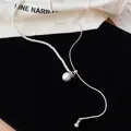 Gedetailleerde weergave van een asymmetrische zilveren ketting met witte parels en kraal - Ronde hanger / Zilver