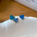 Detailed close-up of asymmetrical blue enamel heart stud earrings with golden edging - Silver Post Gold Blue Stud Earrings