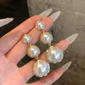 Detail view of French luxury drop earrings with graduated round white pearls in gold frames. - Vertical Tassel Style (HE35725-1) / Pair / Gold with White