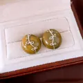 Detailansicht olivgrüner runder Ohrstecker mit silbernen Schleifenakzenten in Schmuckschatulle - 18K Gold Beschichtet / Silber-Grün