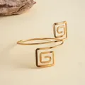 Vue détaillée d'un bracelet de bras doré à spirale carrée géométrique sur fond beige - Or