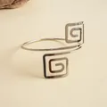Gros plan d'un bracelet jonc ouvert argenté géométrique avec motif de spirale carrée poli - Argent