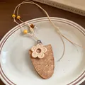 Gros plan d'un collier bohème en cuir et résine avec pendentif à texture de liège - Fleur (Café)