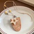 Détail du pendentif étoile bohème et de la texture liège sur un long collier pour pull - Étoile (Marron)