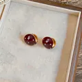 Gedetailleerde weergave van chique rode emaille oorringen met witte stippen design. - Goud-Rood / Rood