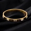 Gros plan d'un jonc en acier titane doré avec zircons baguette sur de la soie - Bracelet à cinq strass blancs dimensionnels (53-B-2)