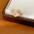 Vue détaillée d'une bague ouverte plaquée or 18k avec zircone ovale et serti de pavés. - Or