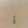 Detailopname van een Franse roestvrijstalen ketting met kralen en metalen kwast - Ketting / Zilver-Koffie
