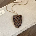 Close-up van vintage luipaardprint hanger ketting op een getextureerde linnen achtergrond - Luipaard Hanger / Koffie-Blauw
