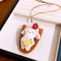 Detail view of a cute plush sheep pendant necklace with leather base and strawberry accent - White