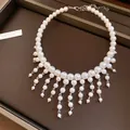 Detailed macro view of a French vintage pearl choker with elegant white tassel droplets - White Pearl