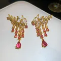 Gros plan de boucles d'oreilles vintage en or avec glands de zircone colorés - Rose Dégradé
