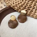 Gros plan détaillé de boucles d'oreilles rondes en bois et métal doré sur toile de lin - Rond / Or, Café