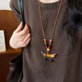 Detail der ethnischen Kette mit Erbsenanhänger und Holzperlen auf braunem Leinenkleid - Halskette-Braun-Gelb