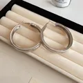 Detail view of chunky silver hoop earrings with a smooth polished finish - Smooth (Small) / Silver