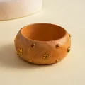 Close-up detail van een retro houten armband met gouden sterren en klinknagels - Ster Klinknagel Stijl