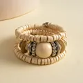 Detailopname van een meerlaagse boho-armband met houten kralen en crèmekleurige bol - Meerlaagse Kralenstijl