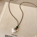Close-up of handmade bird pendant necklace with natural stone beads on a brown cord - Bird