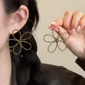 Detailansicht großer blumenförmiger Ohrringe mit gelben Punkten und braunem Finish. - Grau