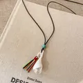 Detailed macro view of ceramic flower pendant necklace with colorful tassel decoration - Tassel Bag Shape