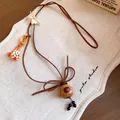 Detailed macro view of the handcrafted wooden dog pendant on a brown cord necklace. - Dog (HN13707) / Brown