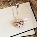 Detailansicht einer süßen Teddybär-Halskette mit Brille auf einem rustikalen Untergrund. - Halskette-Kaffee