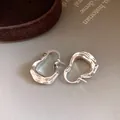 Close-up van zilverkleurige U-vormige oorbellen met een unieke rimpelmetaaltextuur - Oorringen-Zilver