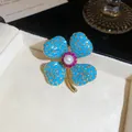 Detail van klavertje vier broche met turquoise kralen en een parel in het middenstuk. - Blauw-Wit
